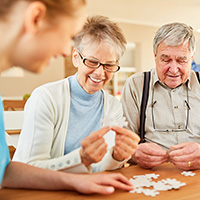 Female and male seniors with blank puzzle pieces guided by female medical professional. 