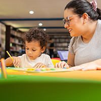 Decorative image of child of color doing hands on activity with adult in library