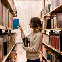 Woman in a library putting books on a shelf