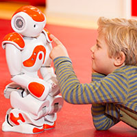 Child playing with an orange and white robot
