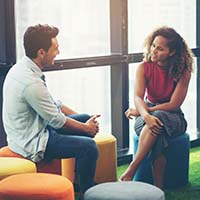 Two people talking while sitting on colorful stools