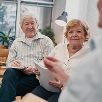 Decorative image of senior-age people with notepads sitting together in a meeting.