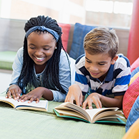 Decorative image of a girl and a boy side-by-side on a couch reading books.