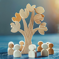 Decorative image of wood cutouts of human figures surrounding tree.