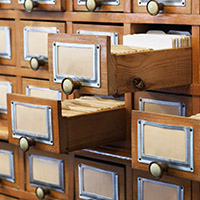 Close-up view of an old-fashioned library card catalog, three drawers opened.