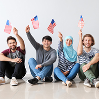 Young adult immigrants waving American flags.